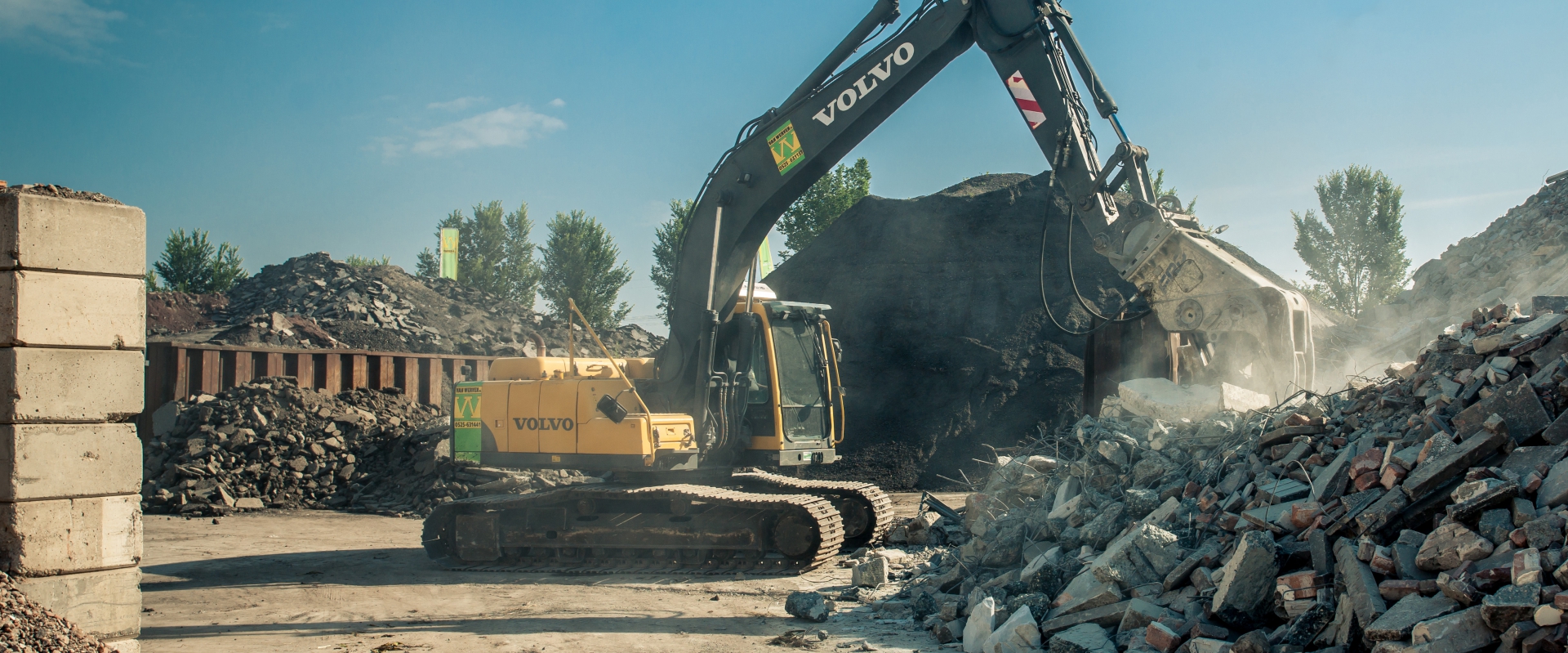 Rupskraan met sloopschaar tussen bergen puin en asfalt op een recyclingvestiging van Van Werven