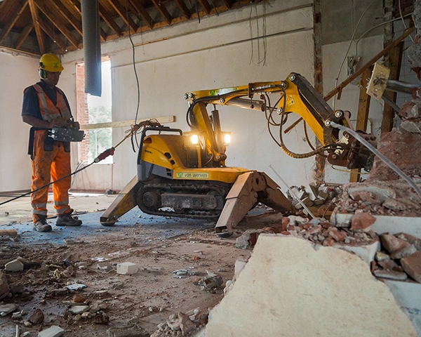 Op afstand bediende slooprobot van Van Werven aan het werk binnen in een pand