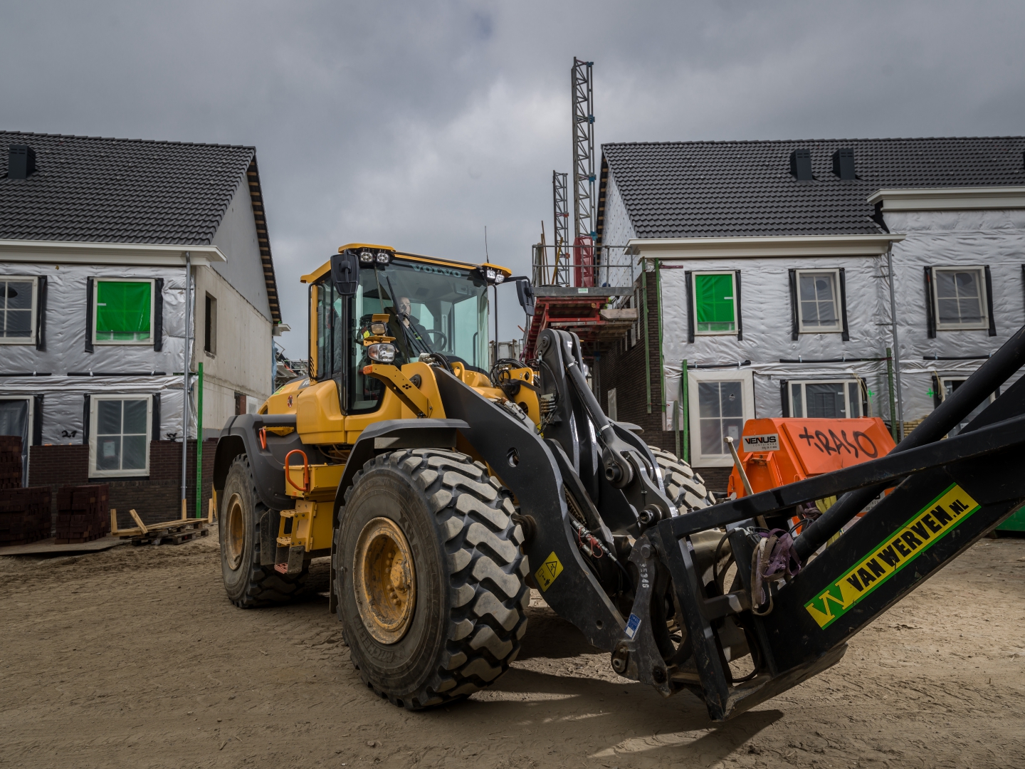 Wiellaadschop van Van Werven met palletvork tussen nieuwbouwwoningen in aanbouw