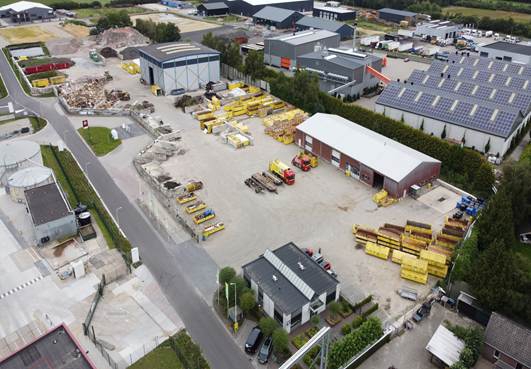Luchtfoto van de recyclingvestiging: rijen gele containers en portaalbakken op een verhard terrein, met loodsen en zonnepanelen eromheen