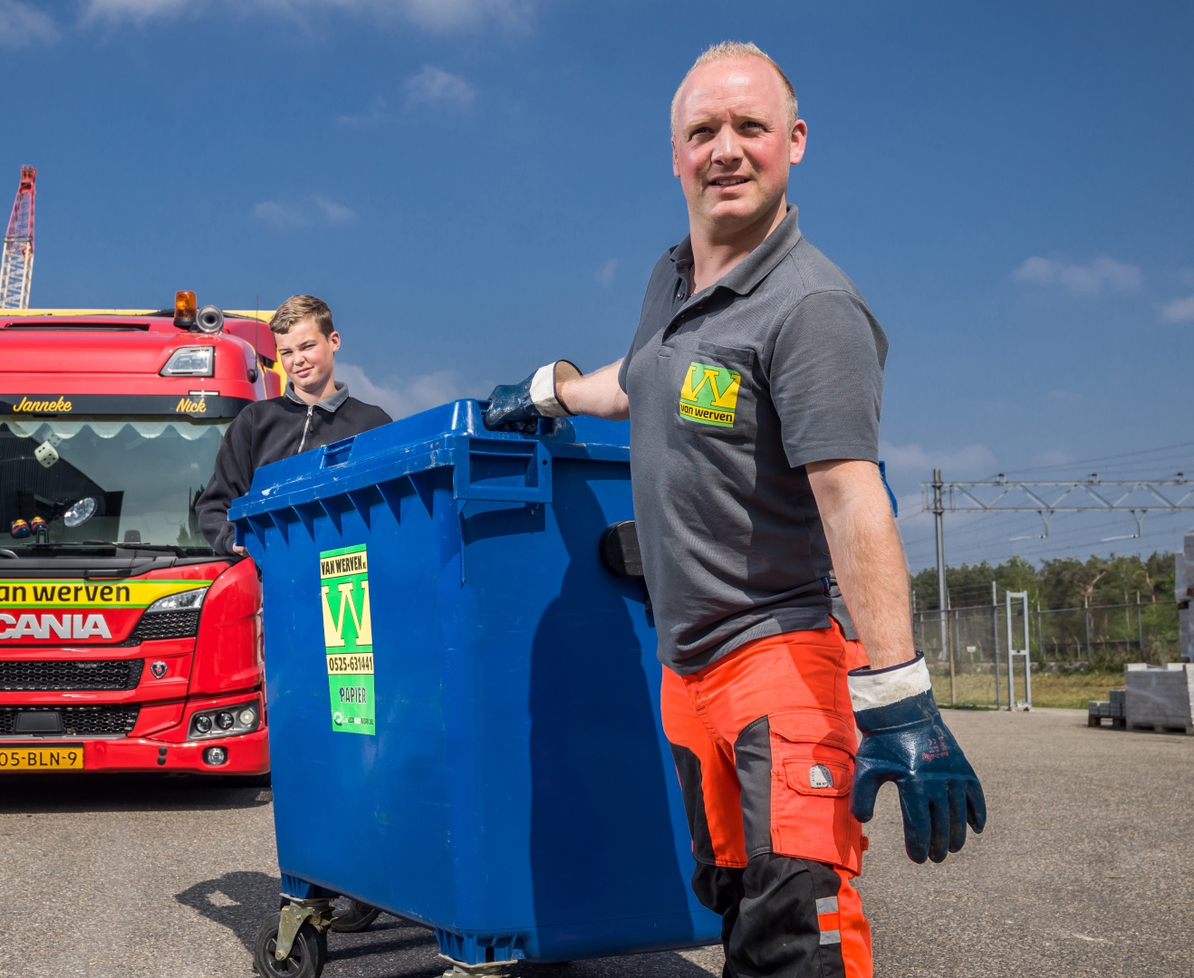 Medewerker van Van Werven rijdt een blauwe kunststof rolcontainer voor papier naar de inzamelwagen