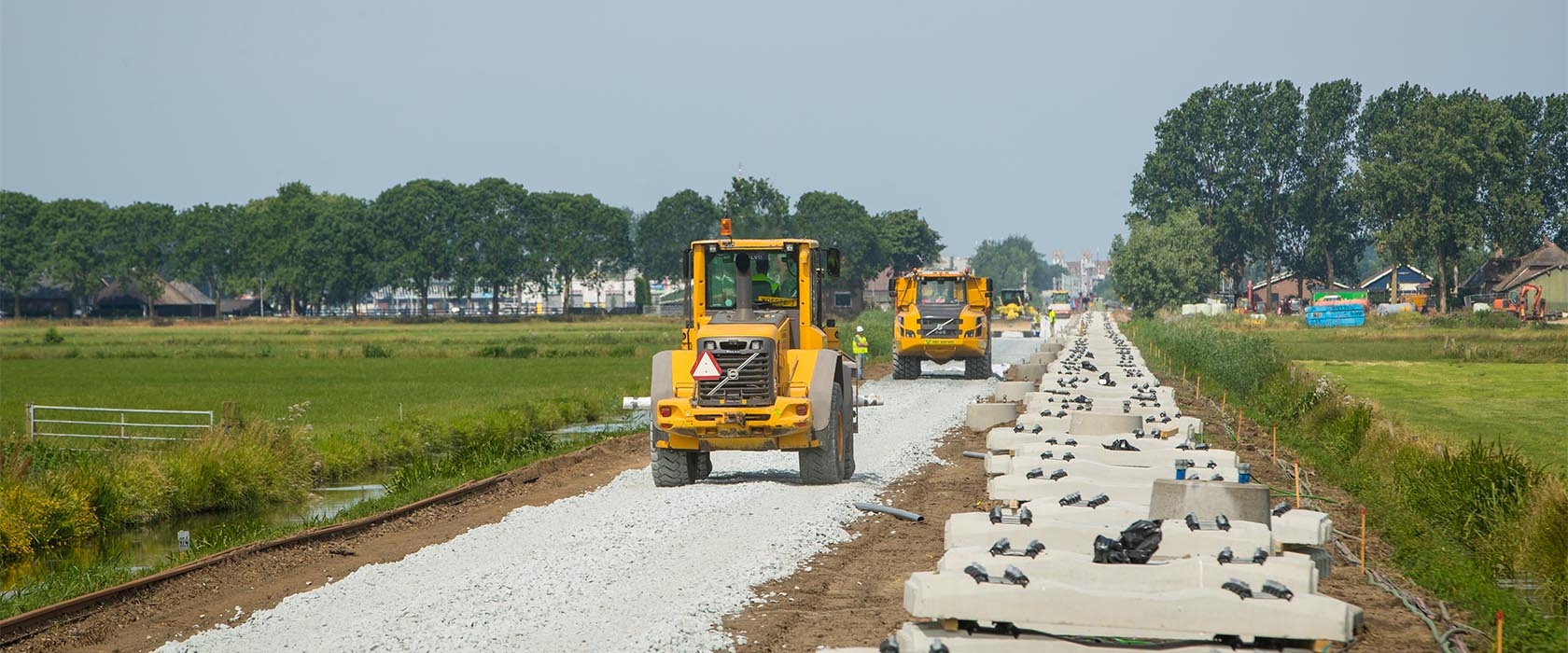 Shovel en dumper op het ballastbed van de Kamperlijn, met dwarsliggers langs het spoor