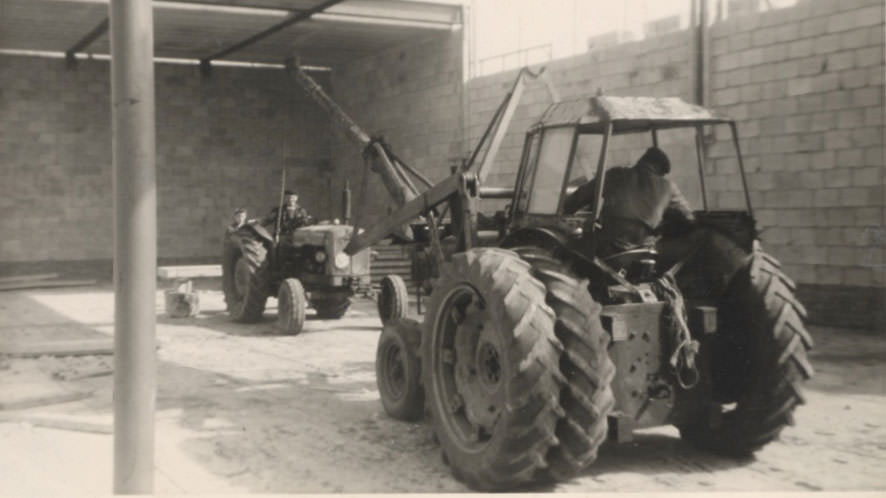 Een tractor met een giek van een boomstam bij de bouw van het zwembad in Wezep