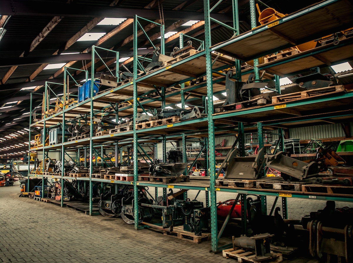 Stellingen vol graafbakken, klemmen en andere hulpstukken in een loods van Van Werven